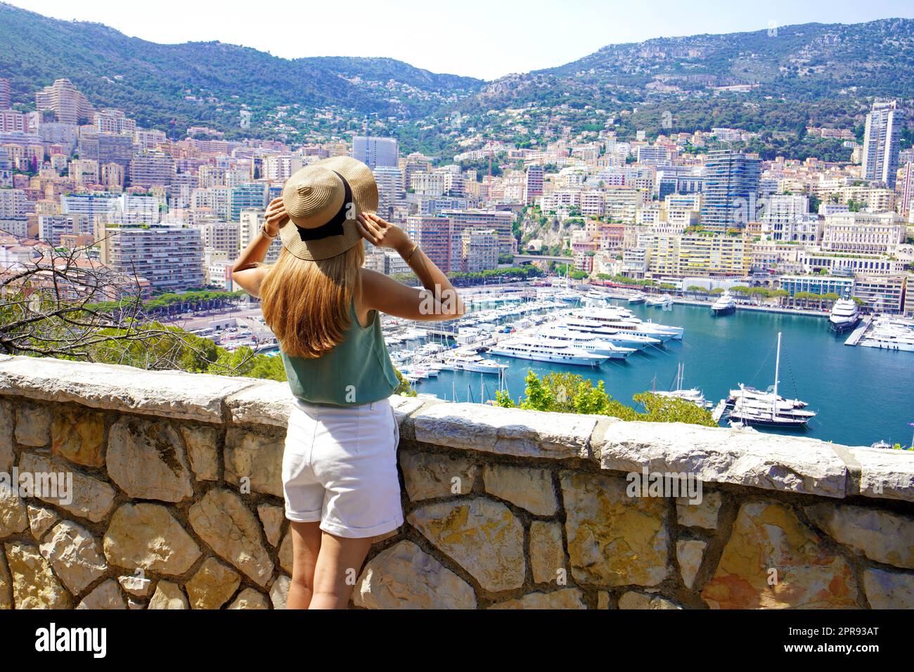 Bella ragazza alla moda che gode di vista sul paesaggio urbano di Monte-Carlo con grattacieli e yacht nel porto, Principato di Monaco Foto Stock