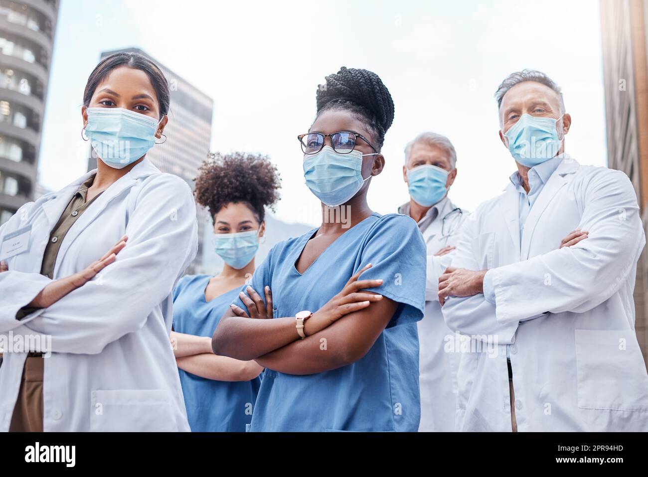 Un gruppo di medici in piedi con le braccia incrociate in città, che ha preso il loro mondo sanitario. Foto Stock