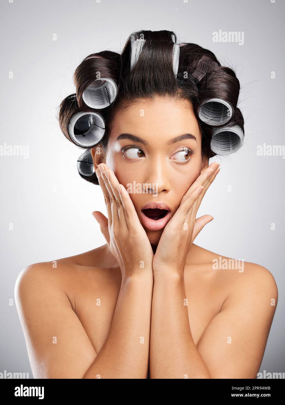 Ho fatto la cosa giusta per i ricci. Studio girato di una giovane donna attraente in posa con arricciatori nei suoi capelli su uno sfondo grigio. Foto Stock