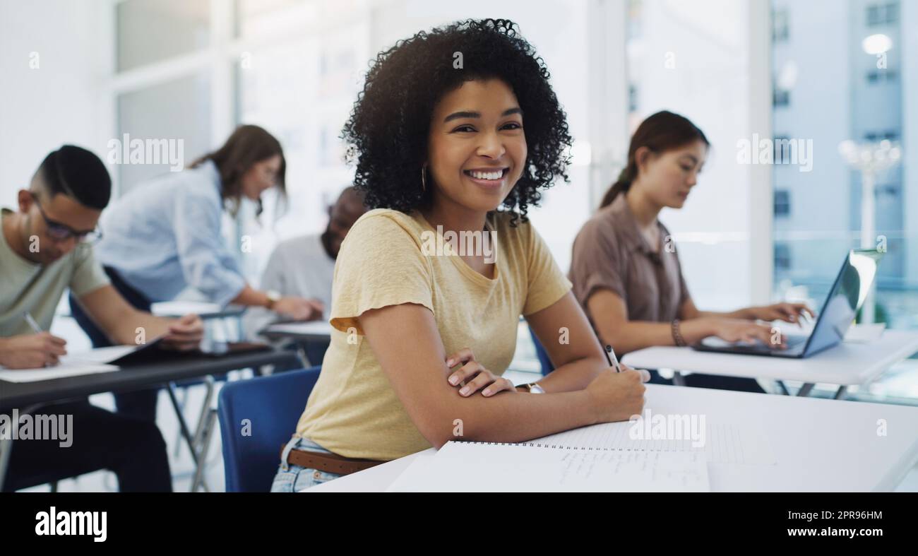Ricercato con ardore e seguito con diligenza. Ritratto di una giovane studentessa felice tra i suoi compagni di classe in un'aula all'università. Foto Stock