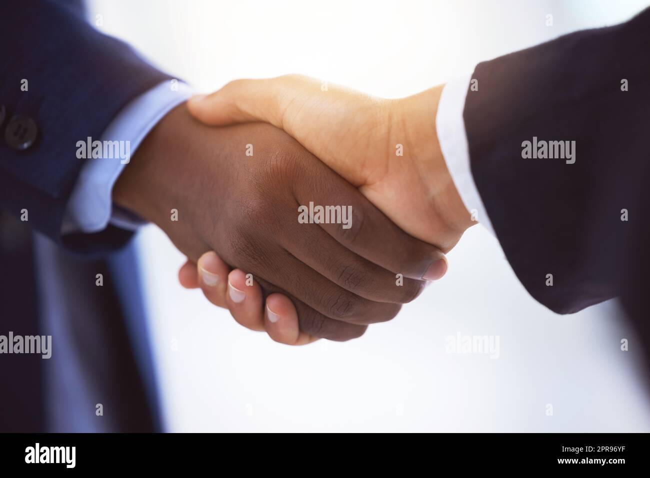 Rimetto il mio giusto pretendente, sono un raro difensore: Due uomini d'affari irriconoscibili che scuotono le mani su uno sfondo bianco sfocato. Foto Stock