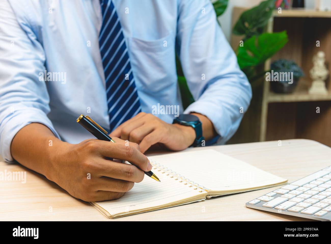Uomo mano che tiene la penna scrivere diario di nota sul libro. Foto Stock