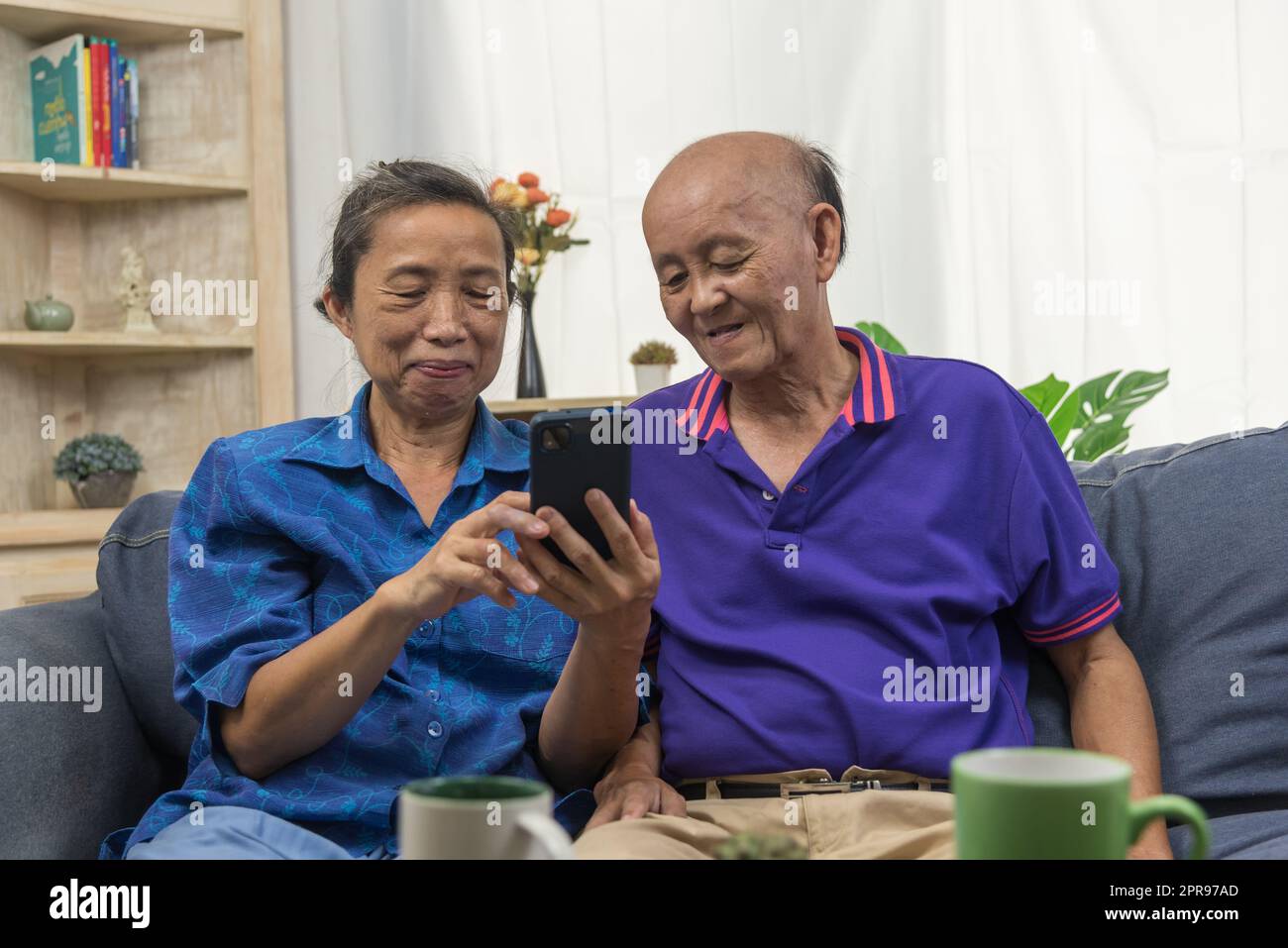 Anziani asiatici che utilizzano la tecnologia di comunicazione internet on-line di connessione al telefono cellulare a casa. Foto Stock