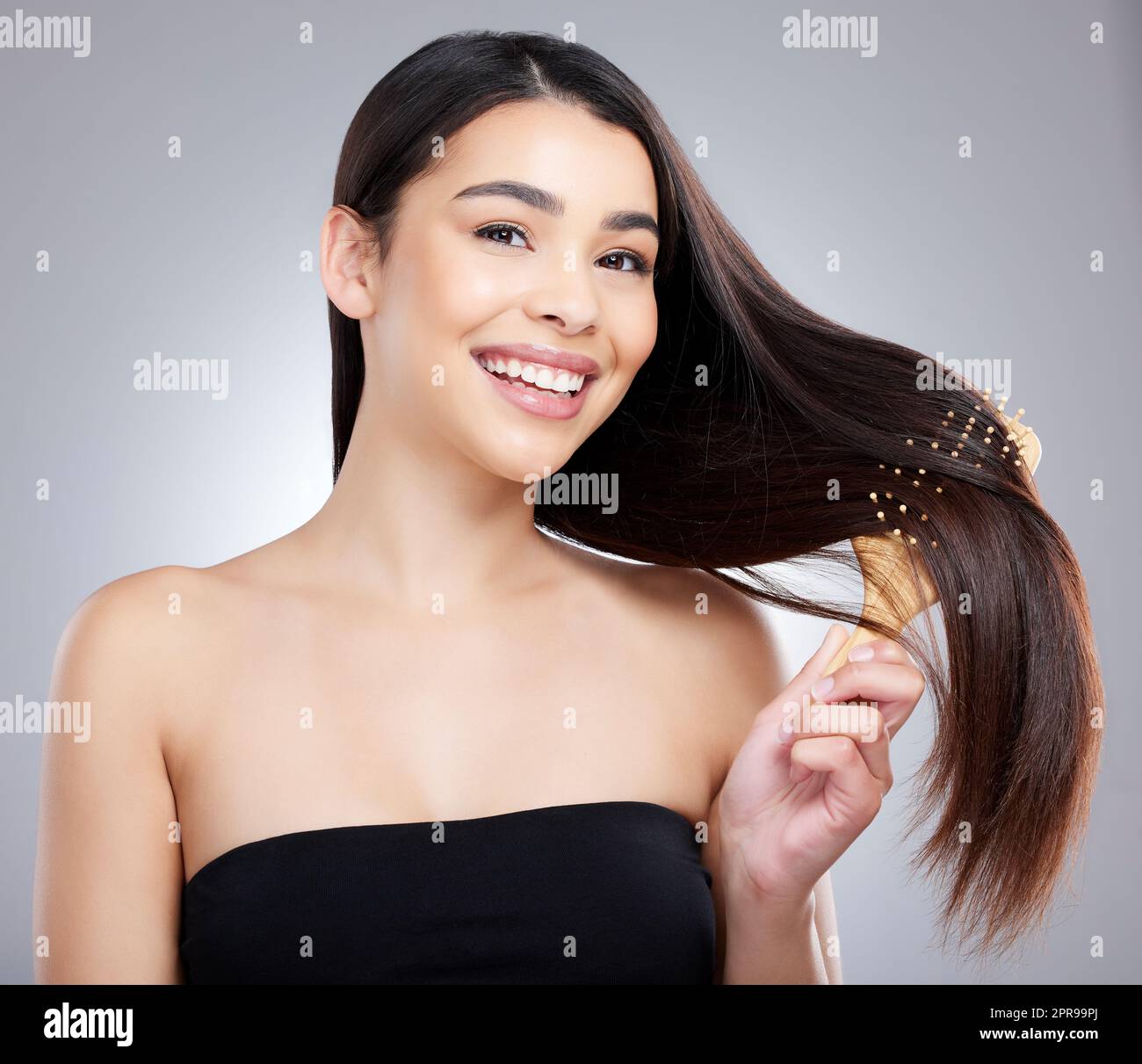 Perché mi rifiuto di affrontare i nodi. Ritratto di studio di una giovane donna attraente spazzolando i capelli su uno sfondo grigio. Foto Stock