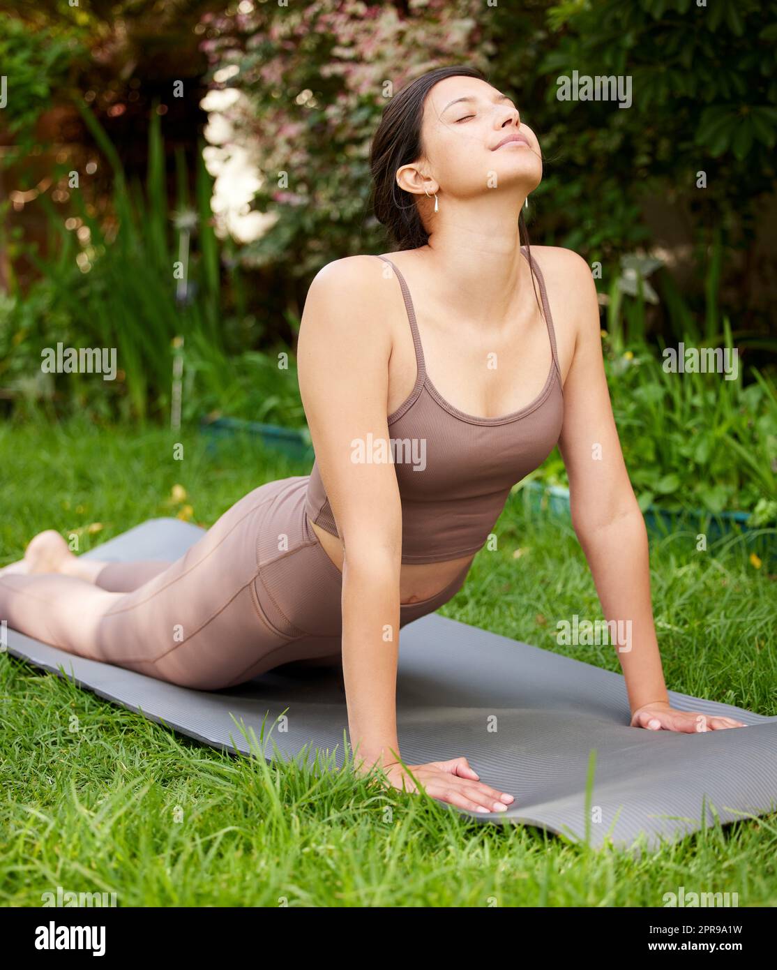 Lo yoga significa mettere la mente e il corpo a proprio agio. Una giovane donna che fa un tratto di cobra mentre si esercita all'aperto. Foto Stock