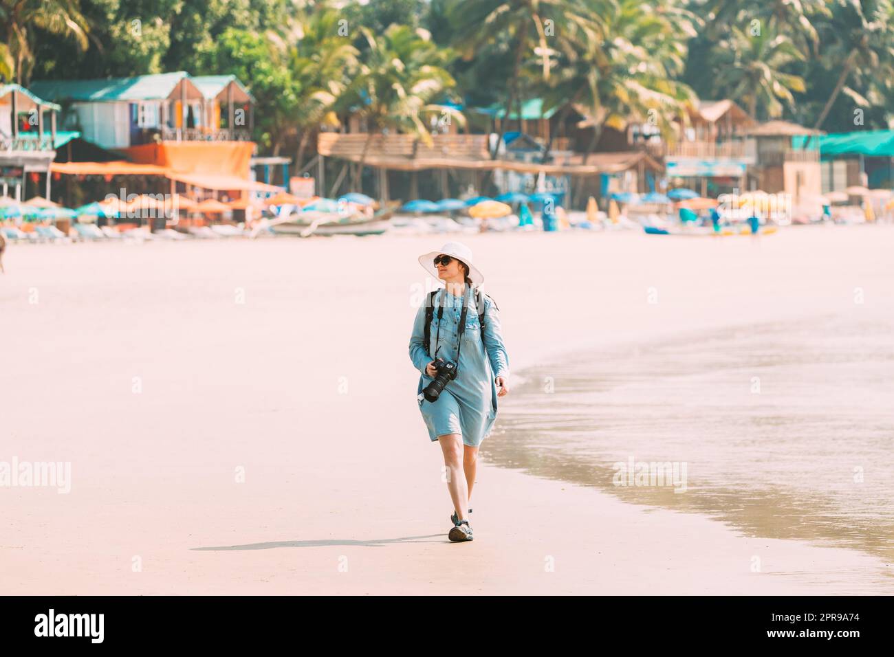 Canacona, Goa, India. Giovane donna caucasica con macchina fotografica a piedi lungo la spiaggia di Palolem in Estate Sunny Day Foto Stock