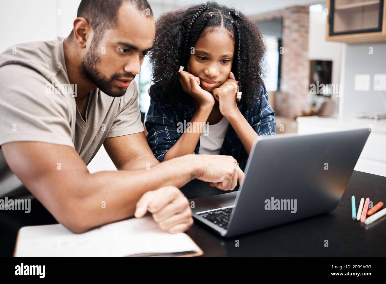 Quando la scuola è lontana, il software educativo è estremamente pratico. Una ragazza giovane che usa un laptop mentre fa un incarico scolastico con suo padre a casa. Foto Stock