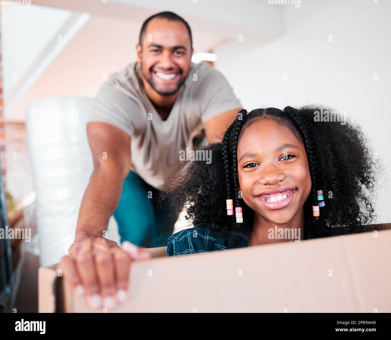 C'era tanto divertimento qui: Un uomo che spingeva la figlia in una scatola di cartone nella loro nuova casa. Foto Stock