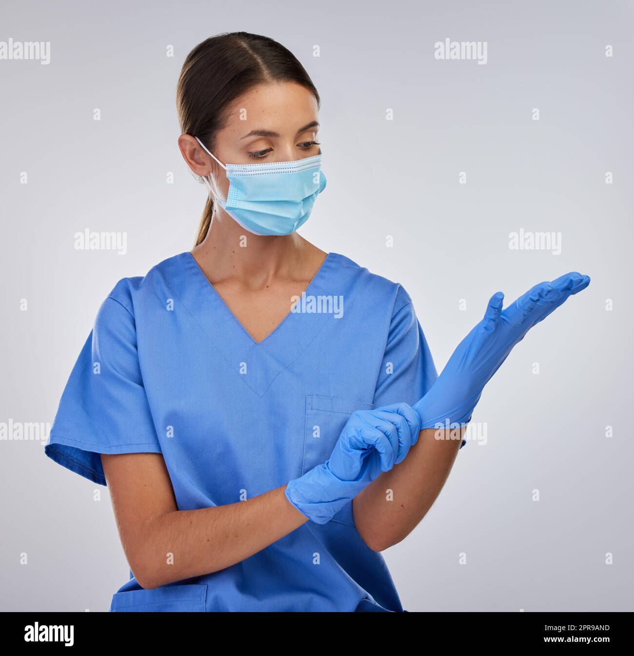 Devo proteggermi a tutti i costi: Un'infermiera donna che indossa i suoi guanti protettivi. Foto Stock
