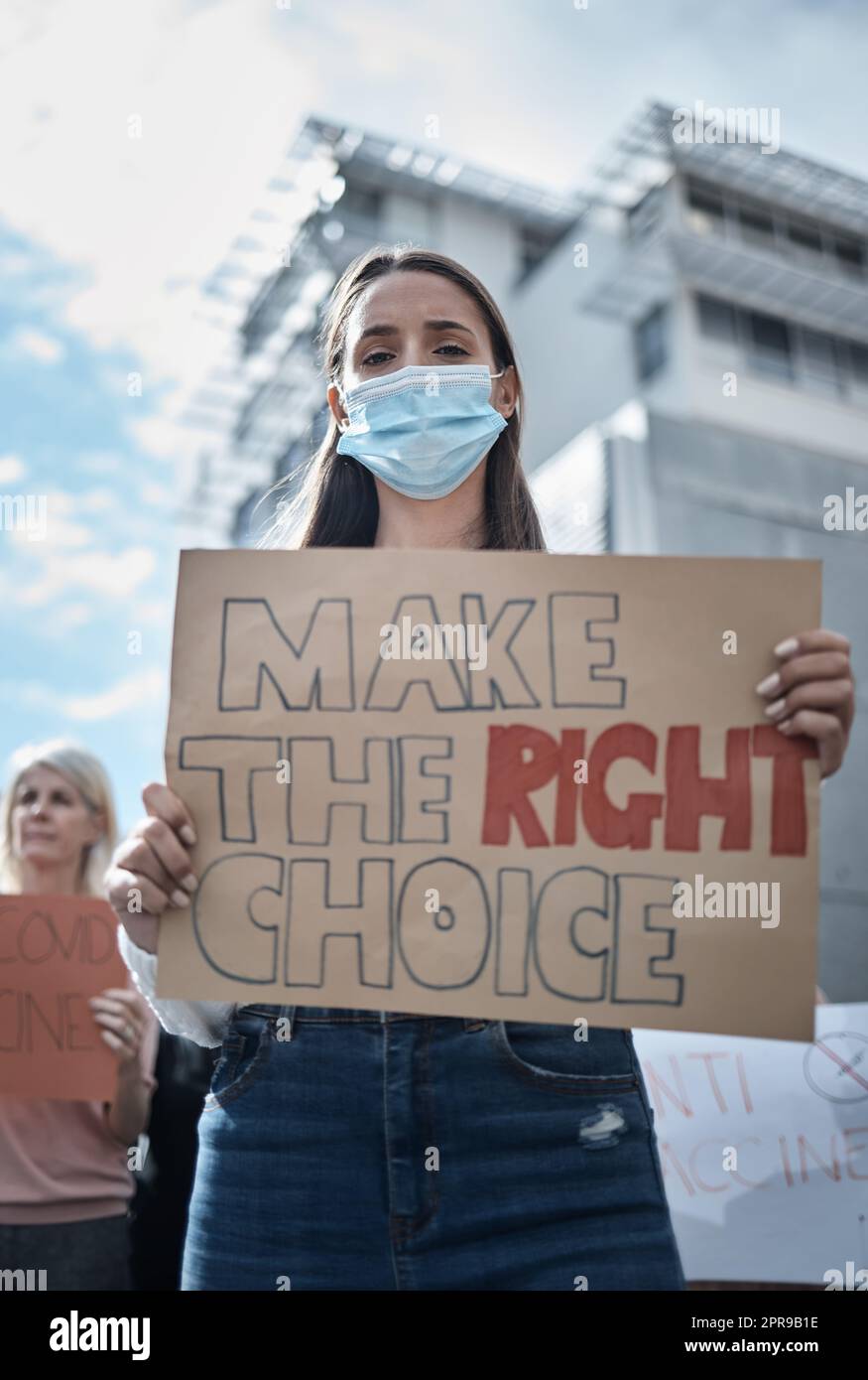 Prendere la decisione giusta per lei, una giovane donna che protestava per una marcia di vaccino covid. Foto Stock