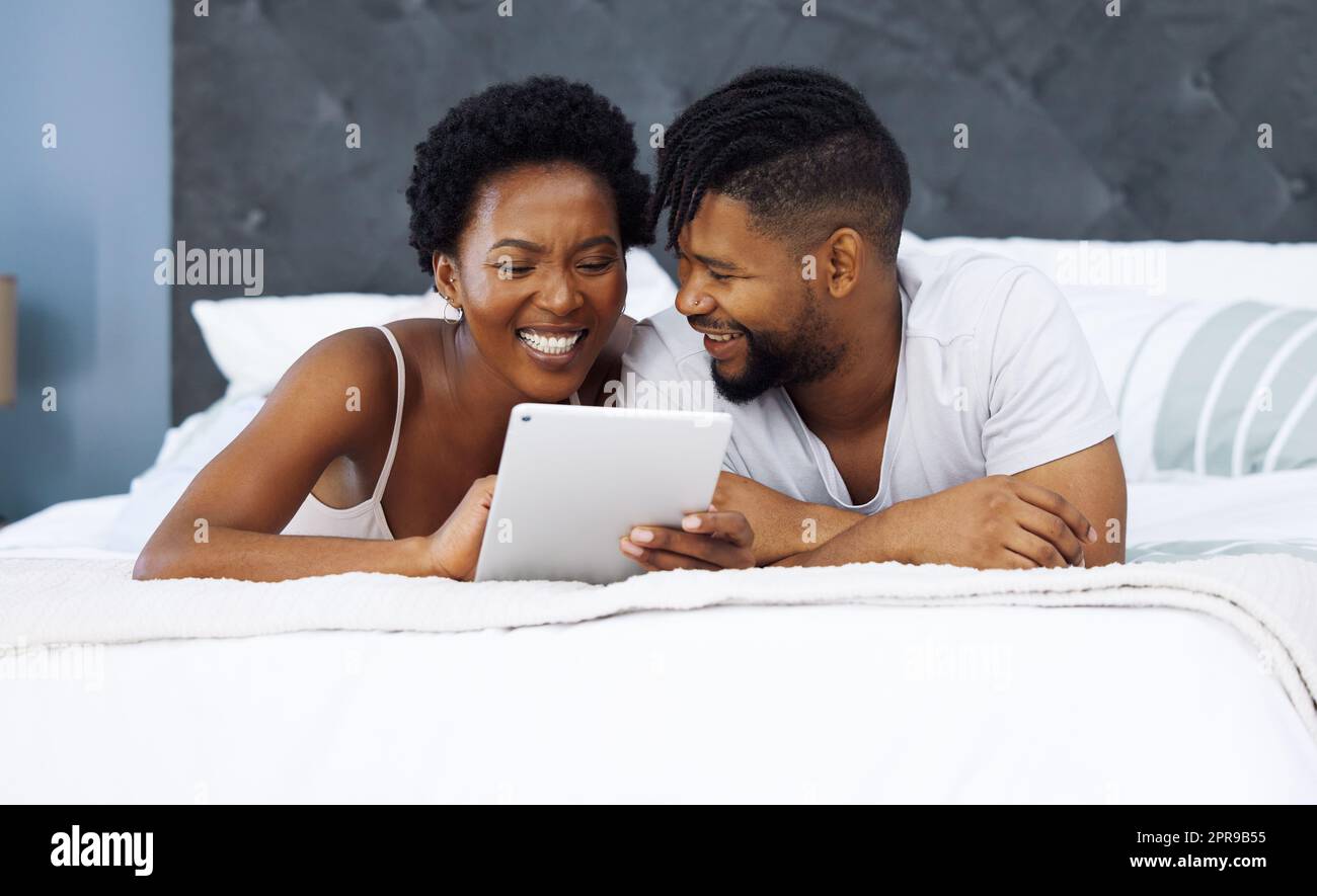 Theres mólto possiamo imparare circa l'amore. Una coppia giovane usando un tablet digitale nel letto nel paese. Foto Stock