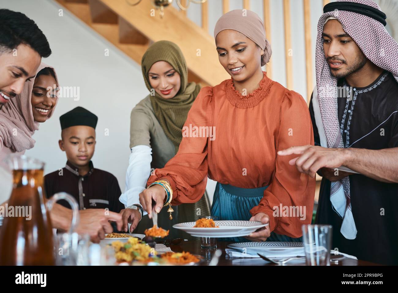 Riempi il tuo piatto. Una famiglia musulmana che si diverte a pranzo. Foto Stock