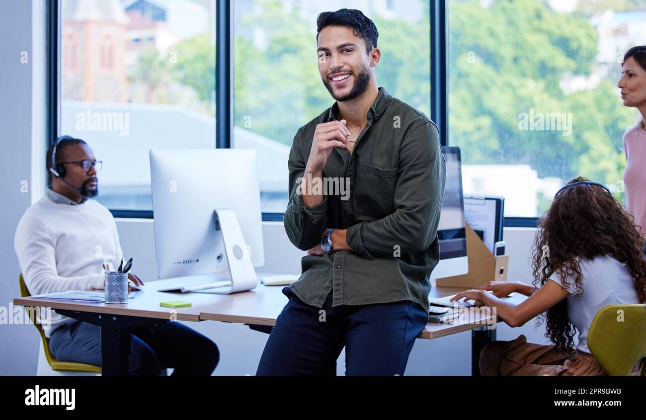 Nel settore della costruzione di grandi marchi. Ritratto di un giovane uomo d'affari in piedi in un ufficio con i suoi colleghi in background. Foto Stock