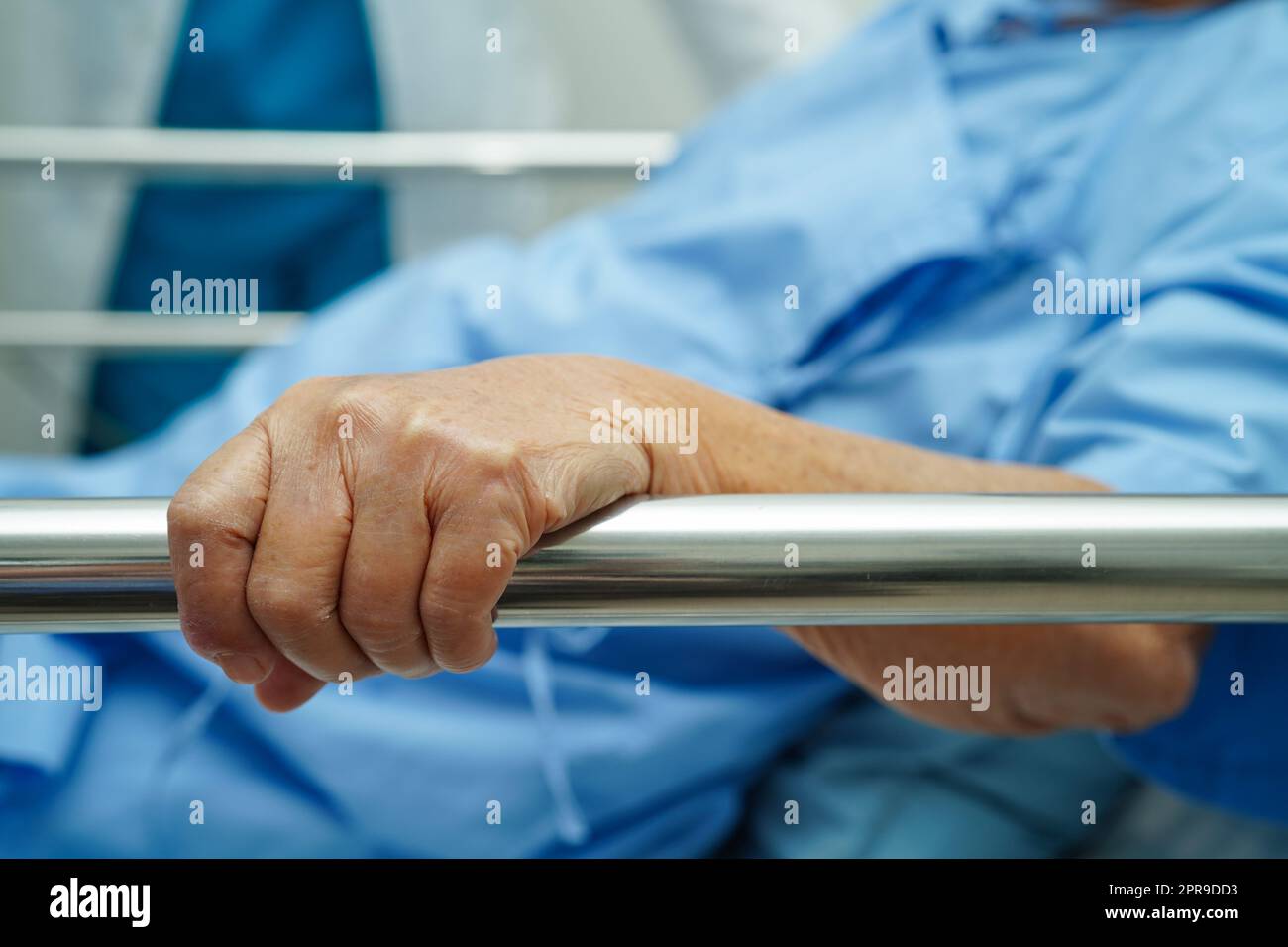 Donna anziana asiatica che tiene la barra del letto mentre si sdraia con speranza in attesa della sua famiglia in ospedale. Foto Stock