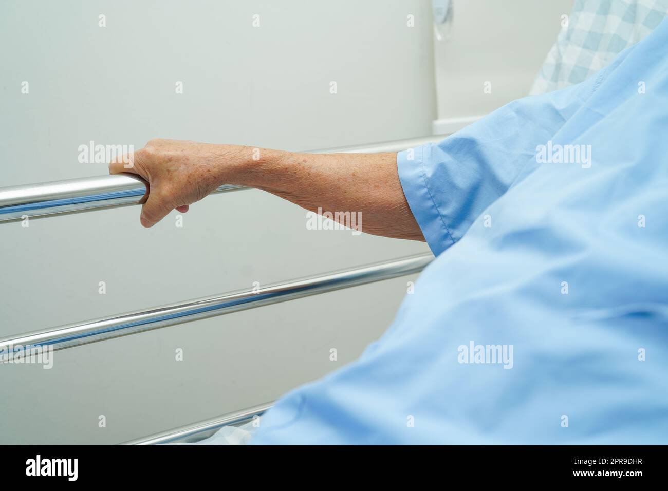 Donna anziana asiatica che tiene la barra del letto mentre si sdraia con speranza in attesa della sua famiglia in ospedale. Foto Stock