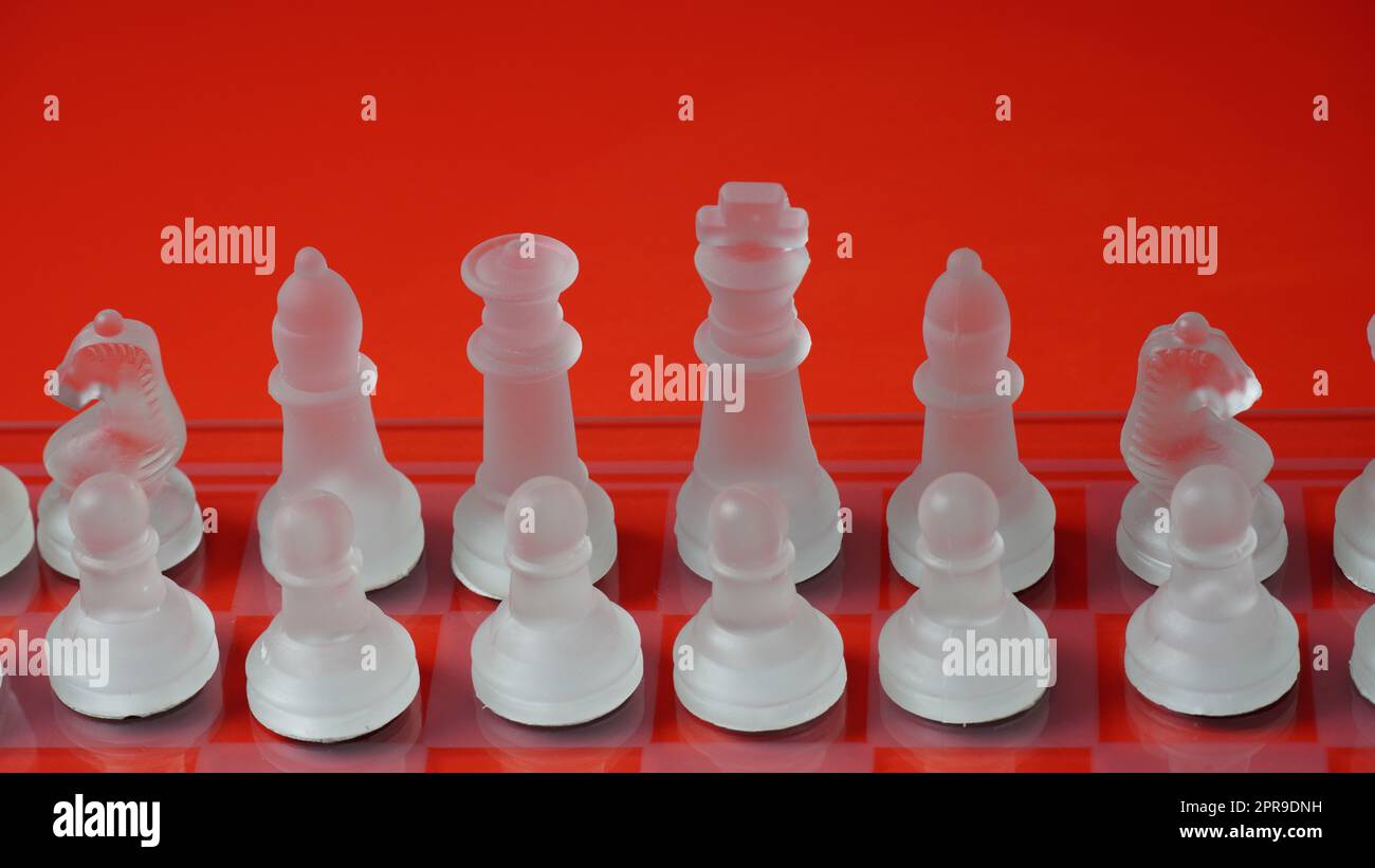 Figure di scacchi trasparenti, in posizione di partenza, su scacchiera riflettente, tono rosso. Gioco da tavolo Scacchi strategico Foto Stock