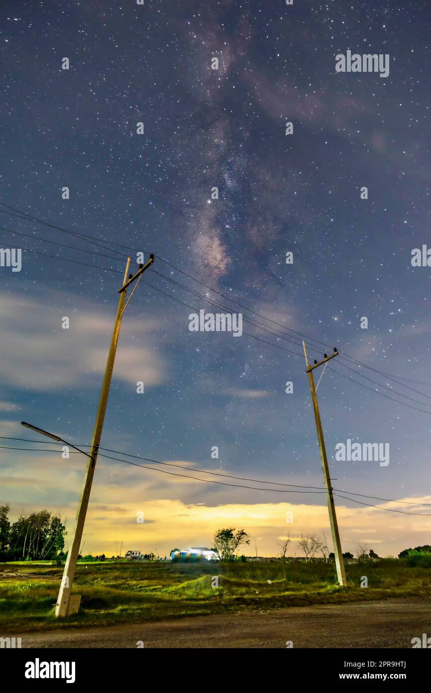 Poli elettrici nel paesaggio notturno, il cielo con le stelle e belle scene di taro, nuvole sotto l'orizzonte sopra l'erba Foto Stock