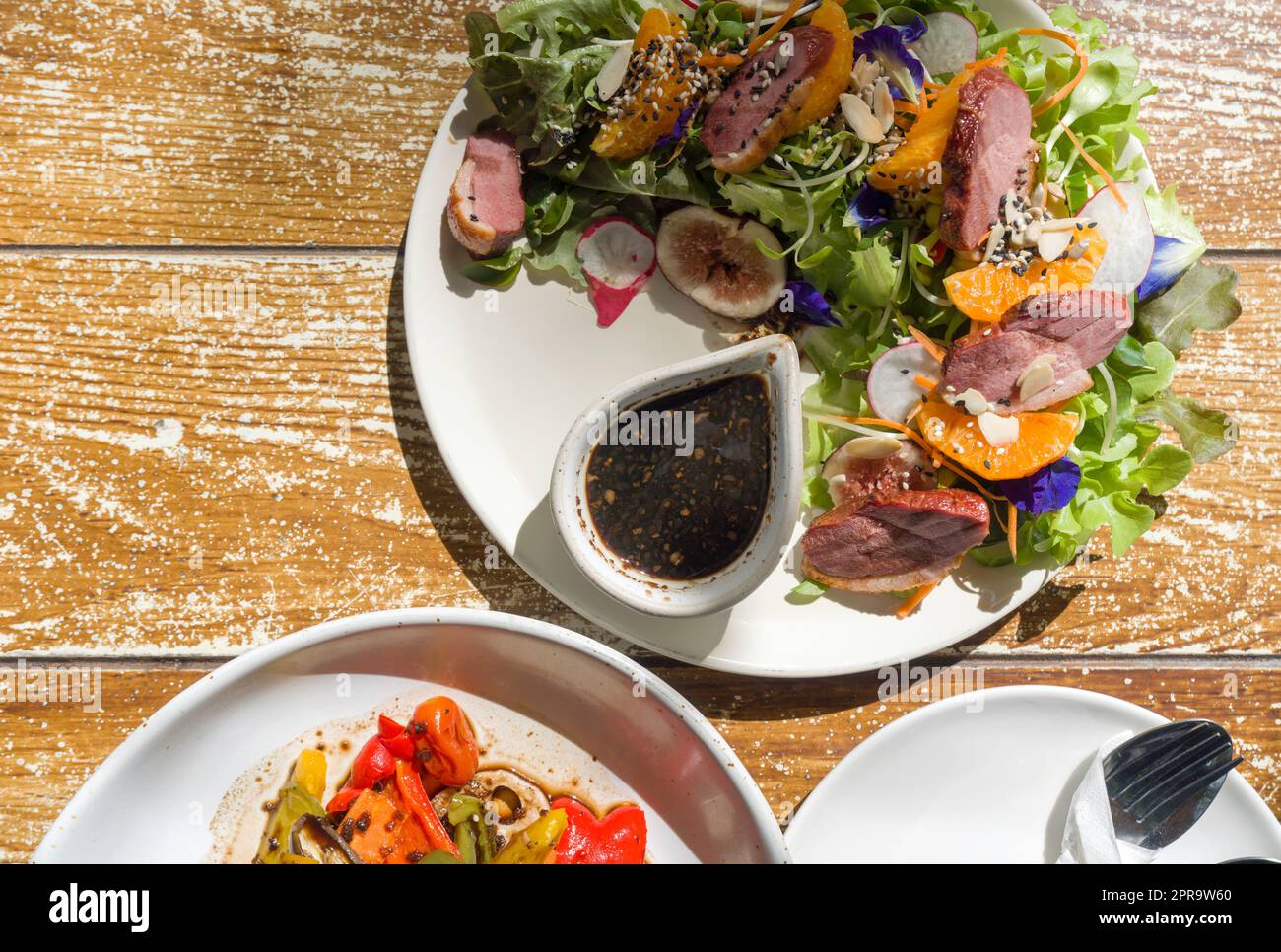 Insalata di petto d'anatra affumicata con salsa balsamica e insalata biologica grigliata servita su tavola di legno. Vista dall'alto Foto Stock