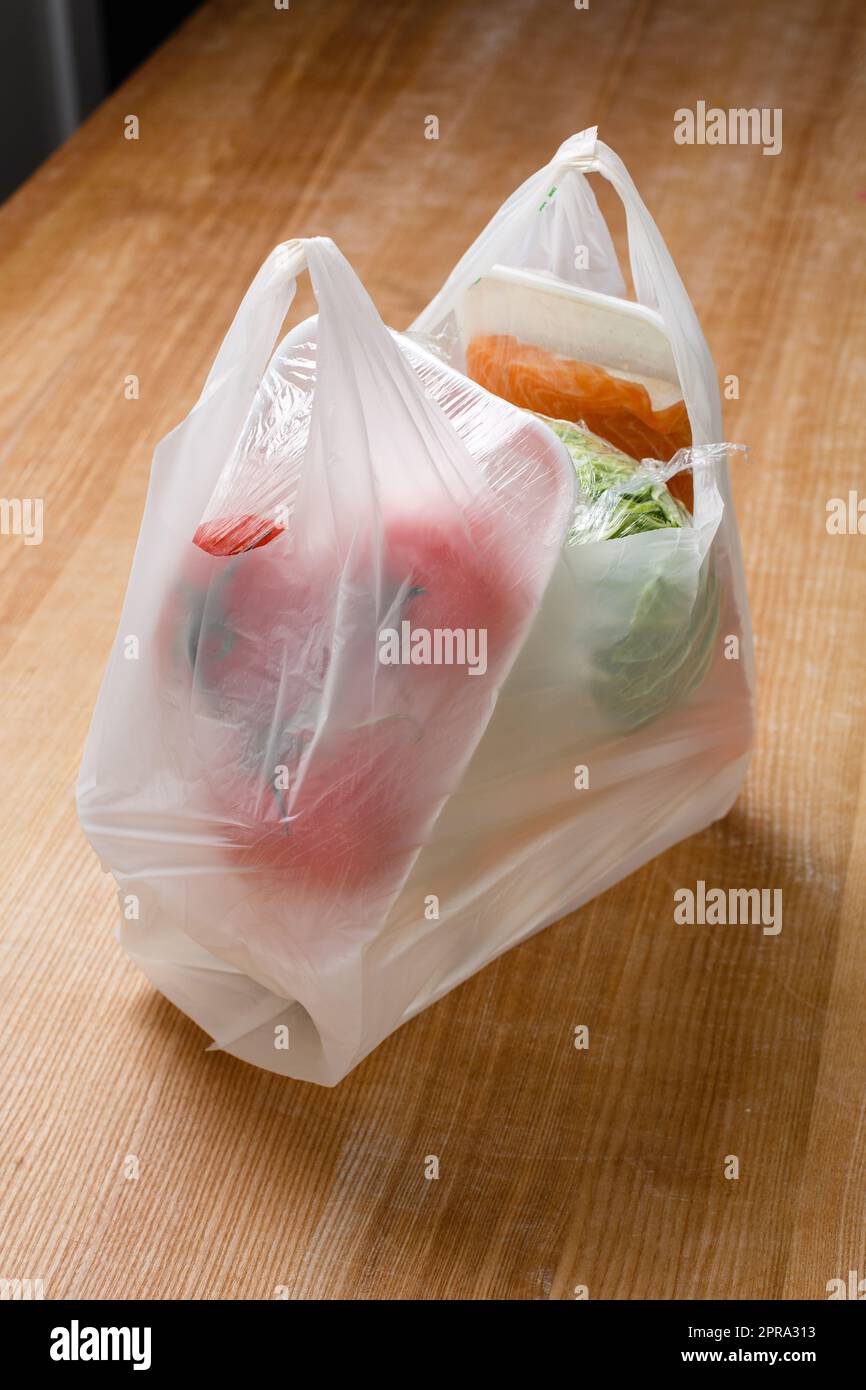 Primo piano del sacchetto di plastica con varie verdure all'interno che sono avvolte in una pellicola trasparente. Foto Stock