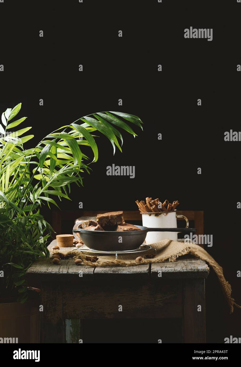 Pezzi di torta di brownie al cioccolato al forno con noci in una padella di metallo nero su un tavolo di legno Foto Stock