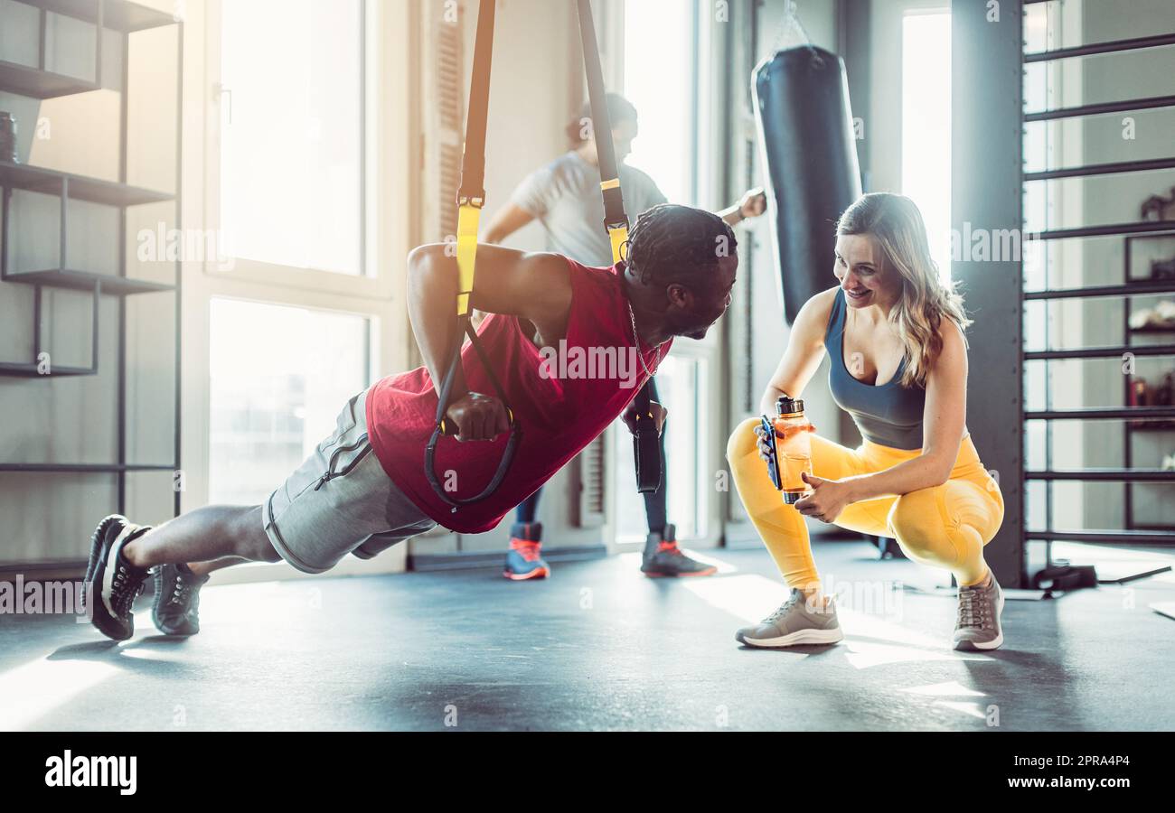 Donna e uomo all'allenatore di imbracatura in palestra Foto Stock