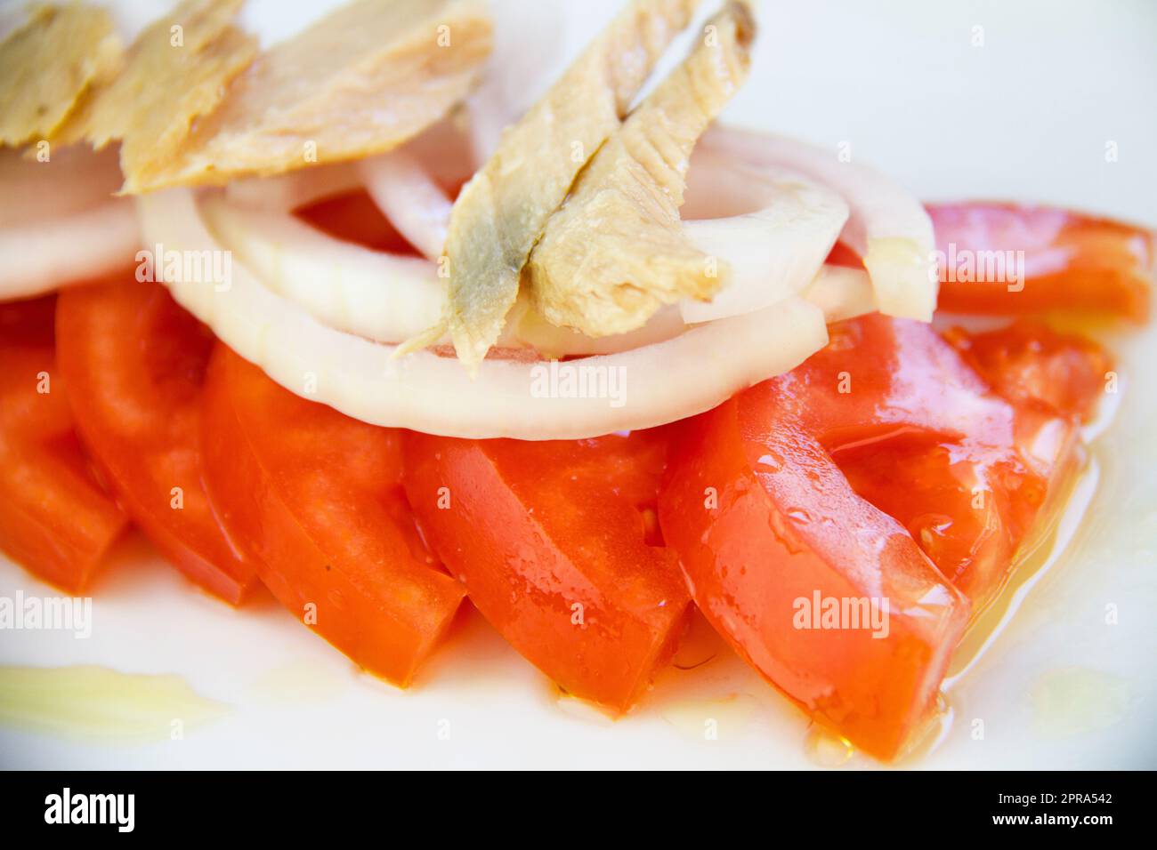 Un piatto di pomodori freschi da fattoria a tavola e insalata, disposti artfully su un piatto bianco Foto Stock