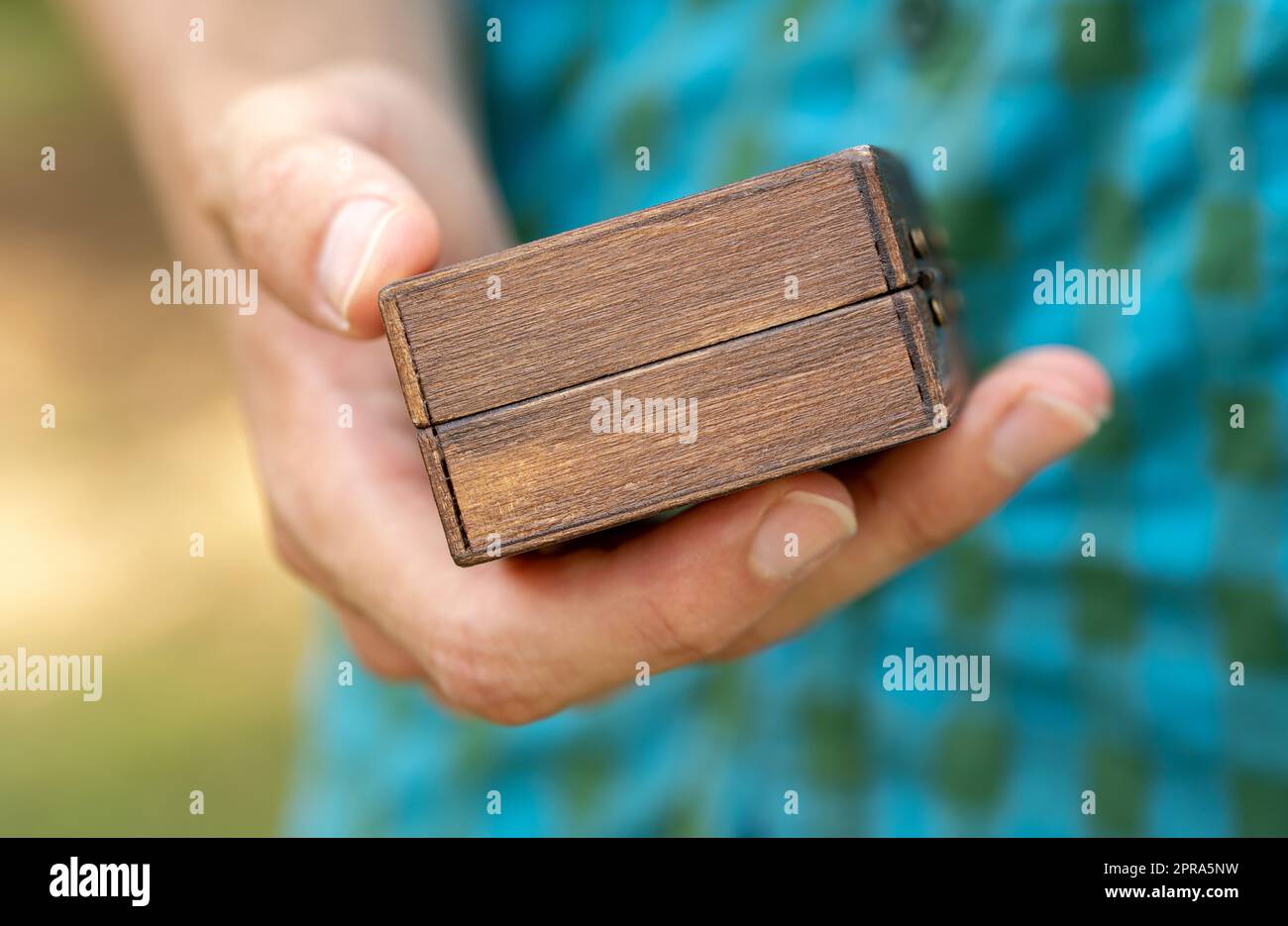 Uomo che tiene un piccolo contenitore generico scatola di legno semplice in mano, particolare, primo piano, scatola del regalo di mistero, regali e regali. Scatola per piccoli oggetti, stoccaggio Foto Stock