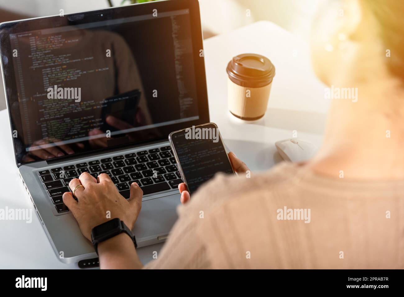 Programmatore donna che guarda il codice di programma del telefono cellulare sul posto di lavoro Foto Stock