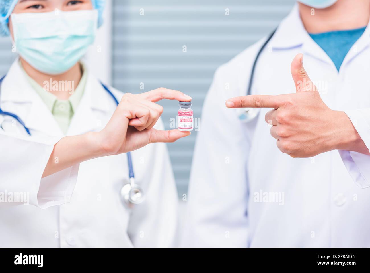 Due medico donna e uomo che tengono fiala corona flacone di vaccino e dito puntato Foto Stock