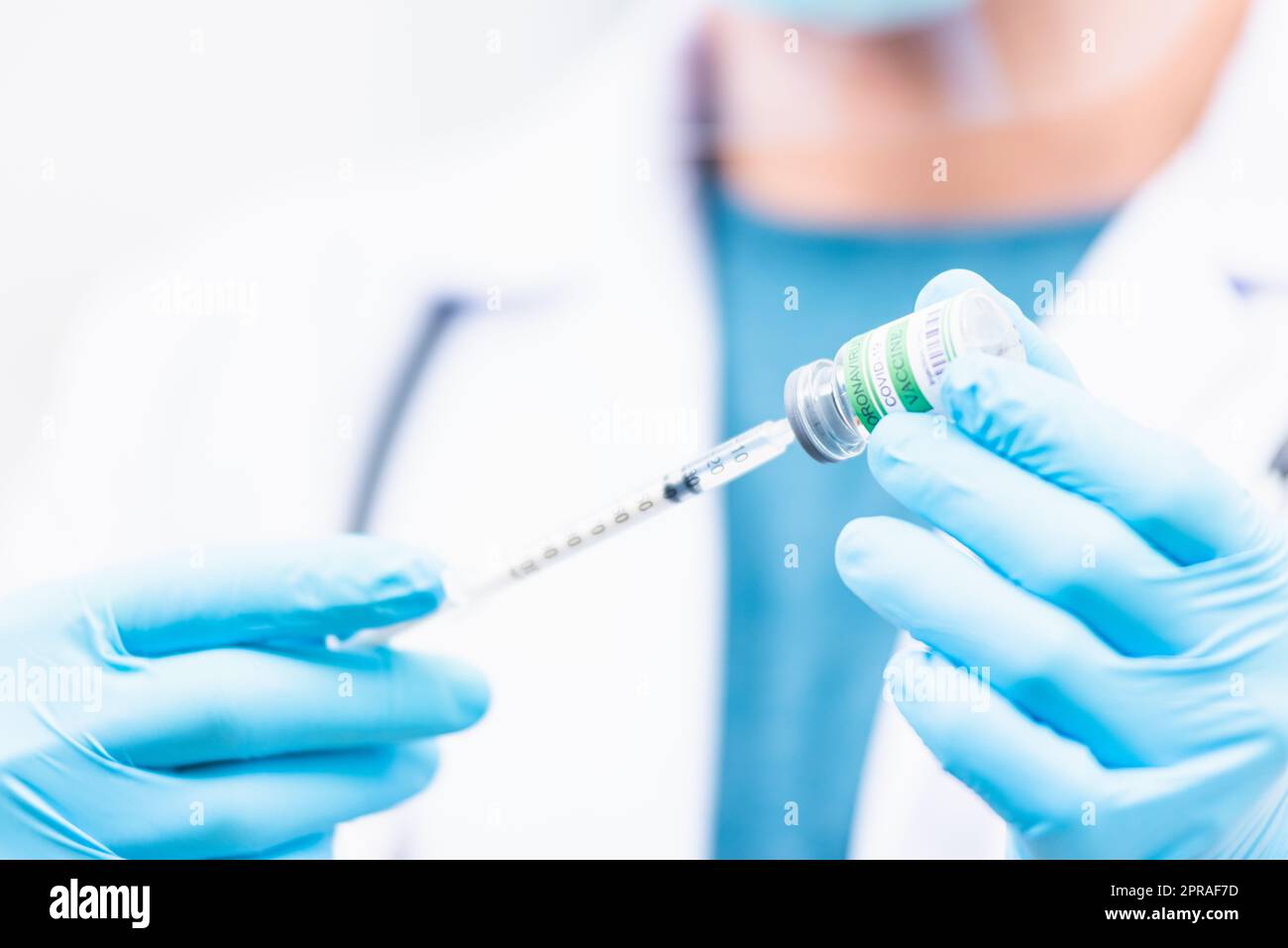 Medico uomo siringa pull sul flacone liquido COVID-19 (coronavirus) vaccino per iniezione in ospedale Foto Stock