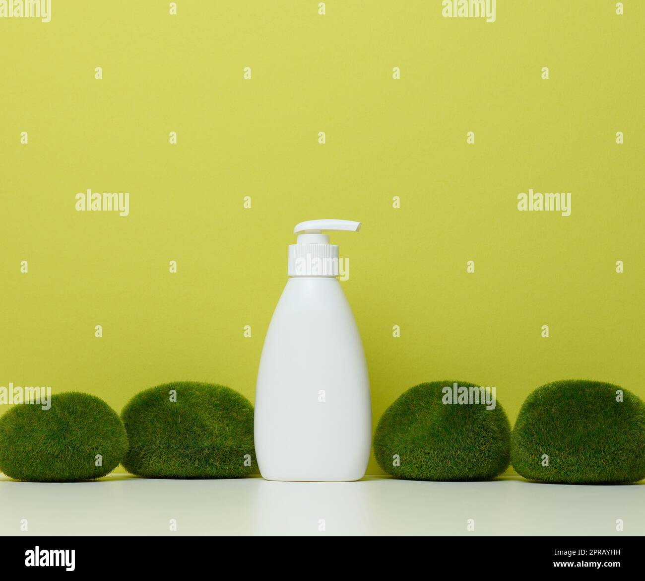 Bottiglia di plastica bianca con pompa su fondo verde. Contenitori per cosmetici Foto Stock