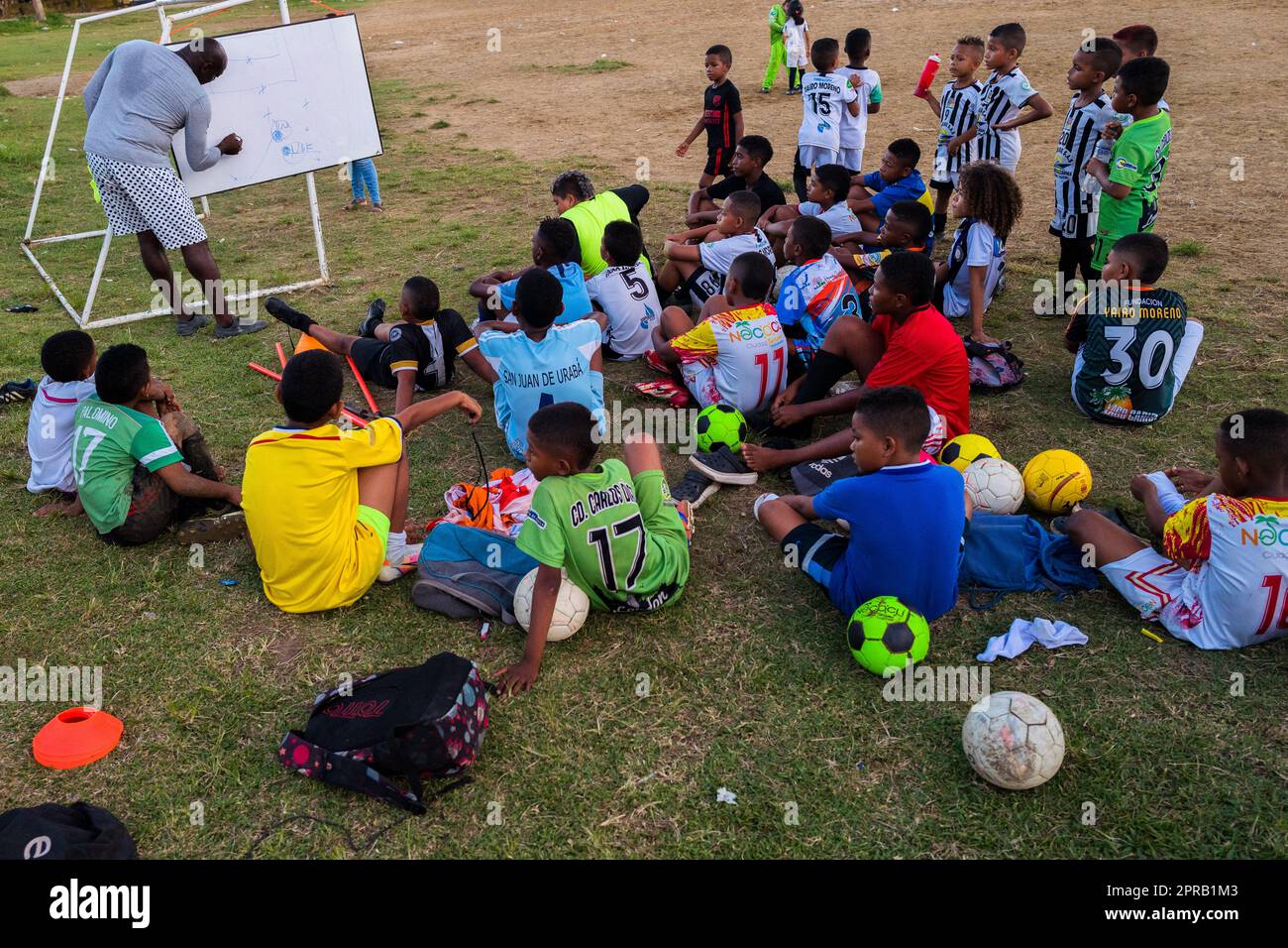 Un allenatore di calcio disegna le situazioni di gioco sulla tavola, mentre i giovani giocatori afro-colombiani guardano durante una sessione di allenamento a Necoclí, Antioquia, Colombia. Foto Stock