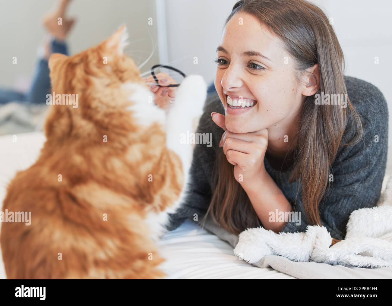 Godendo una giornata pigra con il suo amico più lontano, una giovane donna che gioca con il suo gatto a casa. Foto Stock
