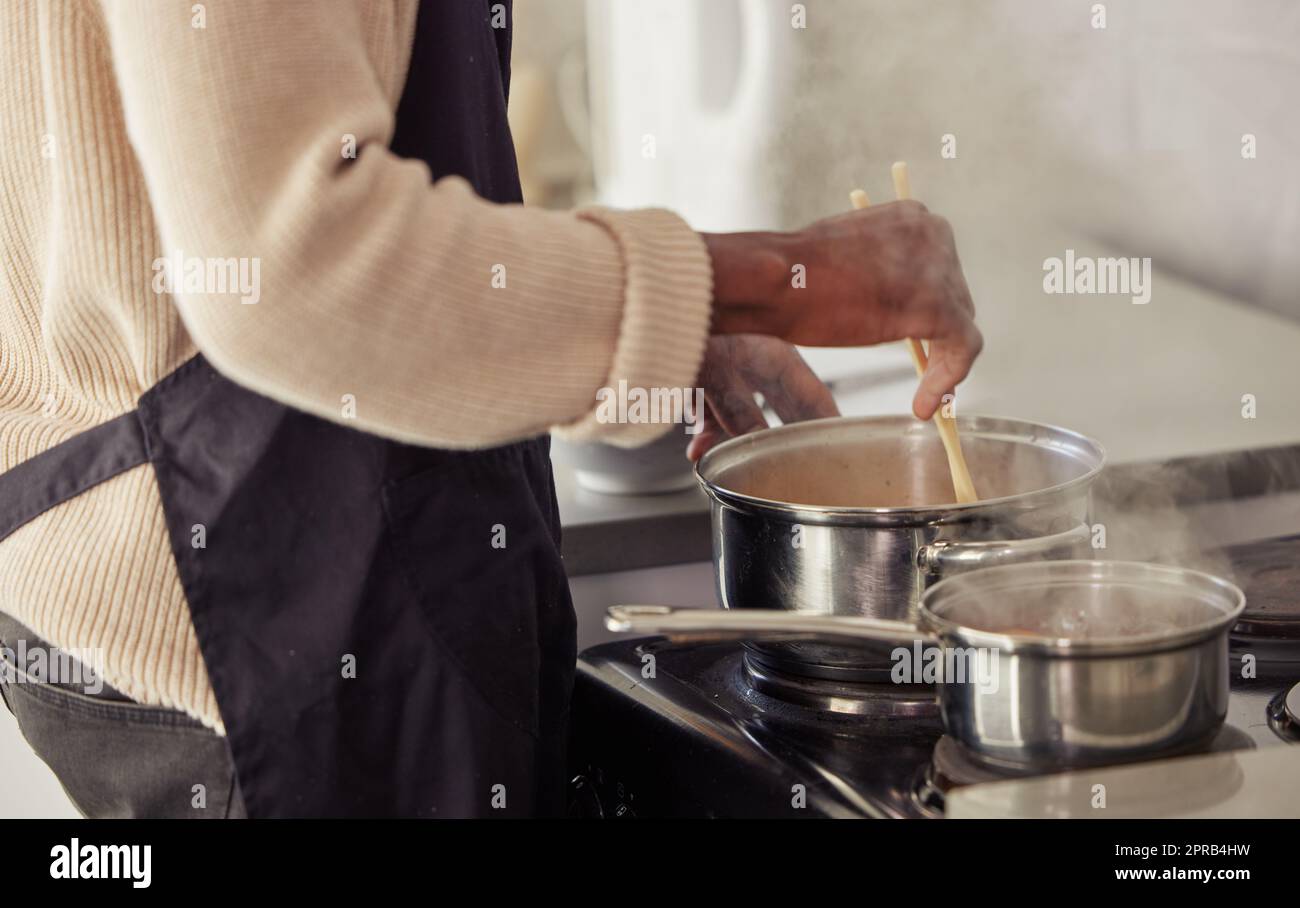 La cucina è dove fa il suo lavoro migliore. Un uomo irriconoscibile che cucinava sulla sua stufa nella cucina di casa. Foto Stock