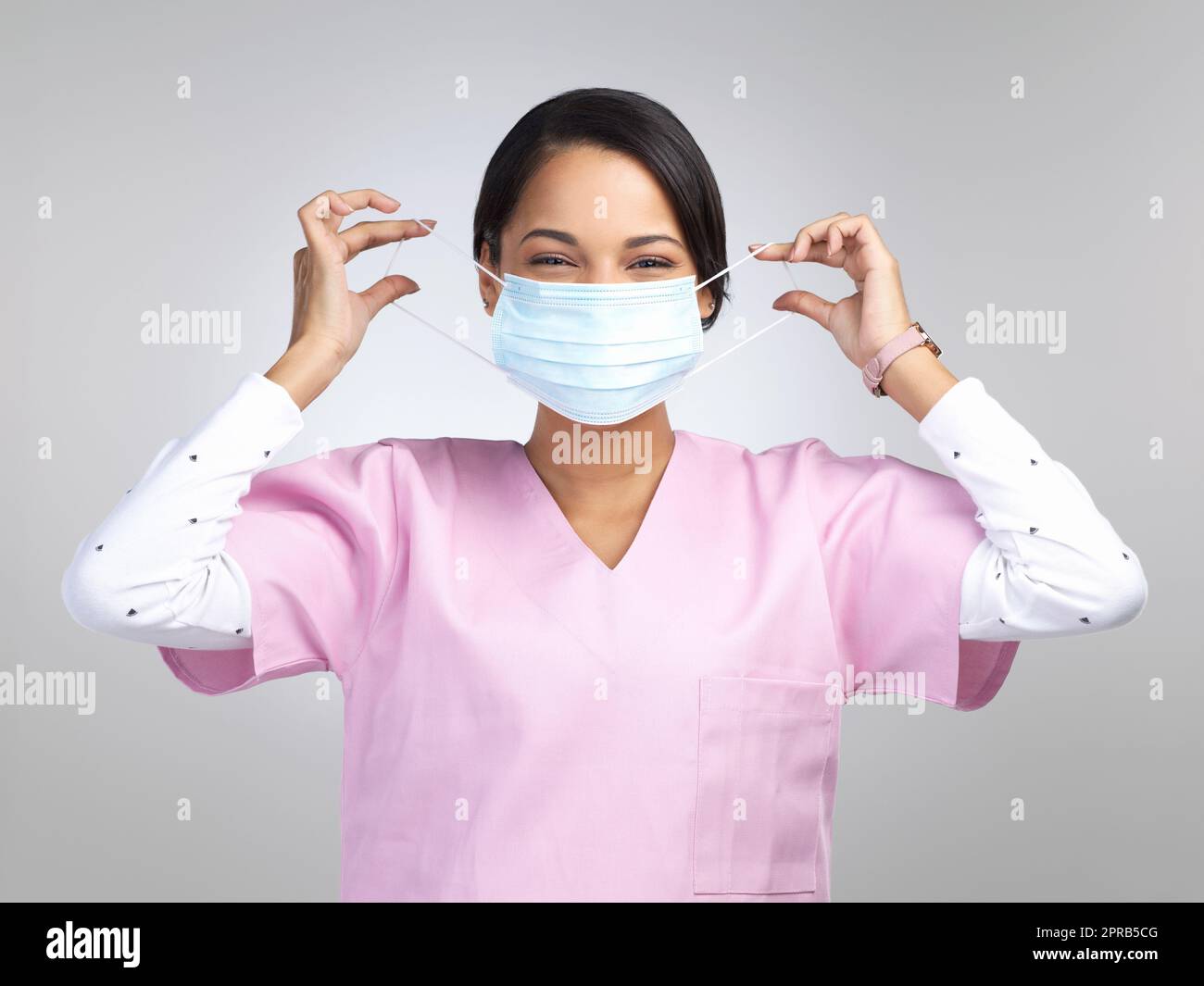 Non me ne vado mai di casa senza. Ritratto ritagliato di una giovane attraente lavoratrice sanitaria che indossa una maschera e sta in piedi in studio su uno sfondo grigio. Foto Stock