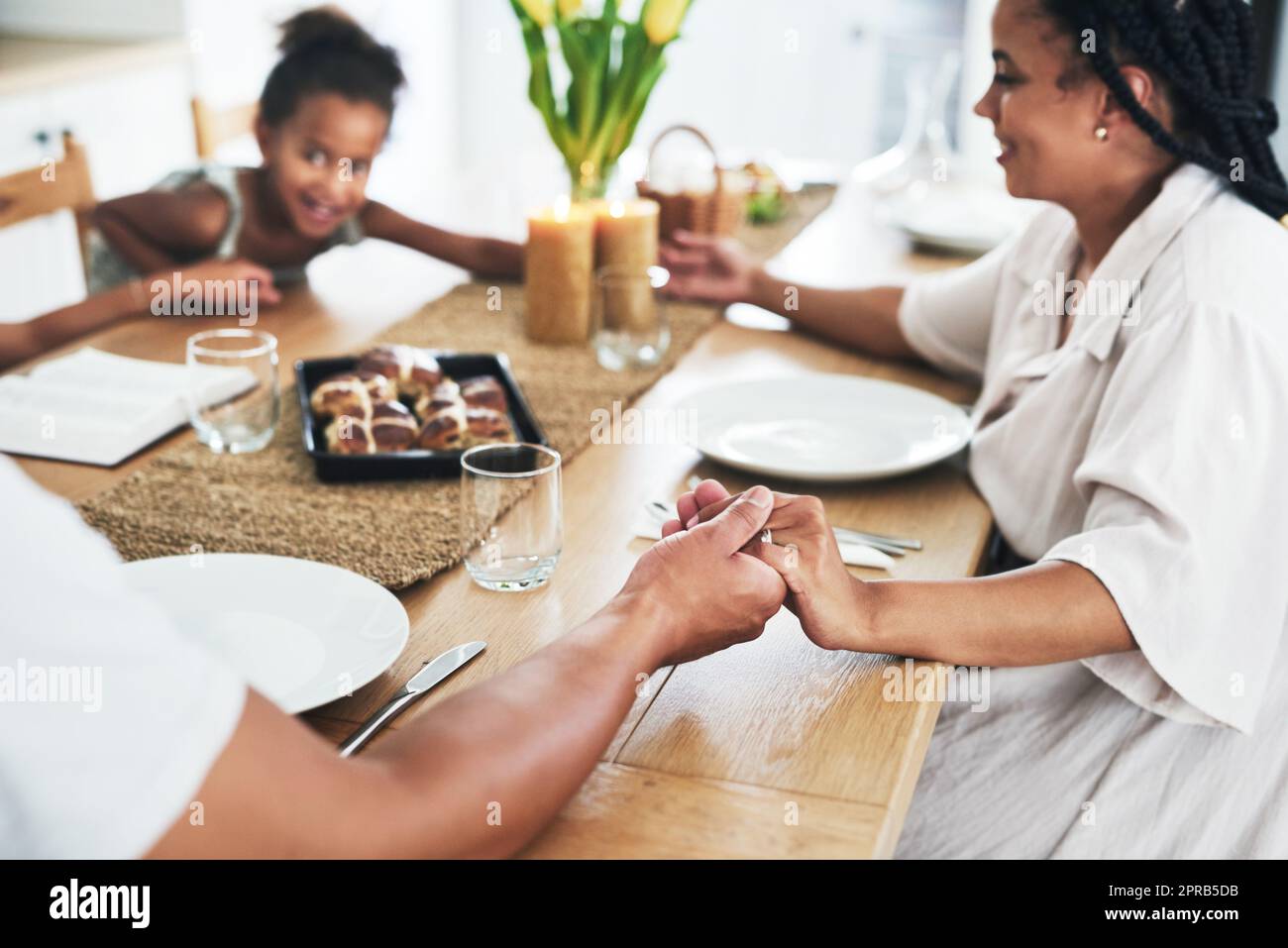 Benedire il pasto che è stato preparato, una famiglia irriconoscibile che tiene le mani durante il tempo di preghiera a casa. Foto Stock