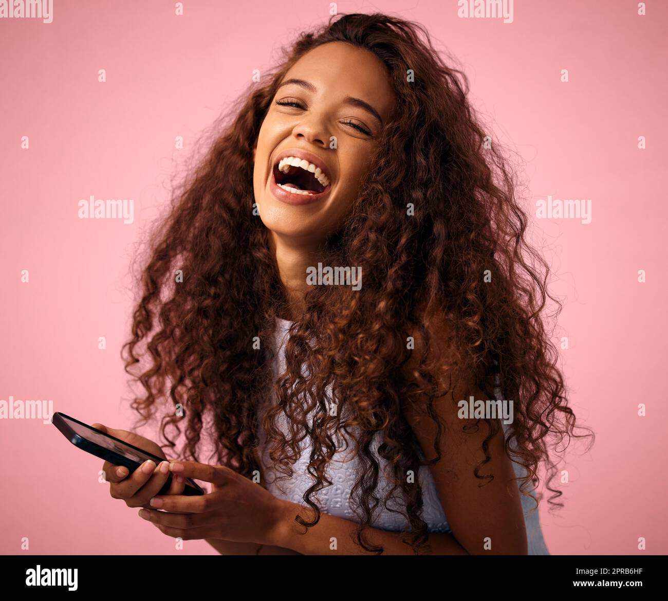 ID consente di scorrere i memo tutto il giorno. Studio girato di una bella giovane donna utilizzando il suo cellulare mentre in piedi su uno sfondo rosa. Foto Stock