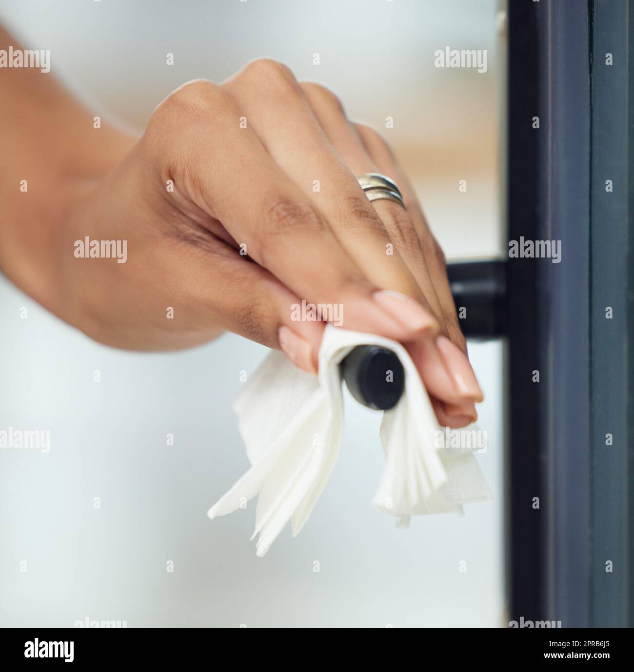 Se lo avete toccato, im pulirlo. Una donna irriconoscibile che pulisce una maniglia della porta. Foto Stock