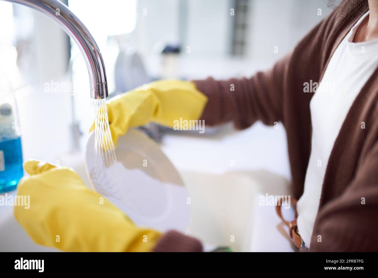 A nessuno piace una cucina sporca, una donna irriconoscibile che lava i piatti a casa. Foto Stock