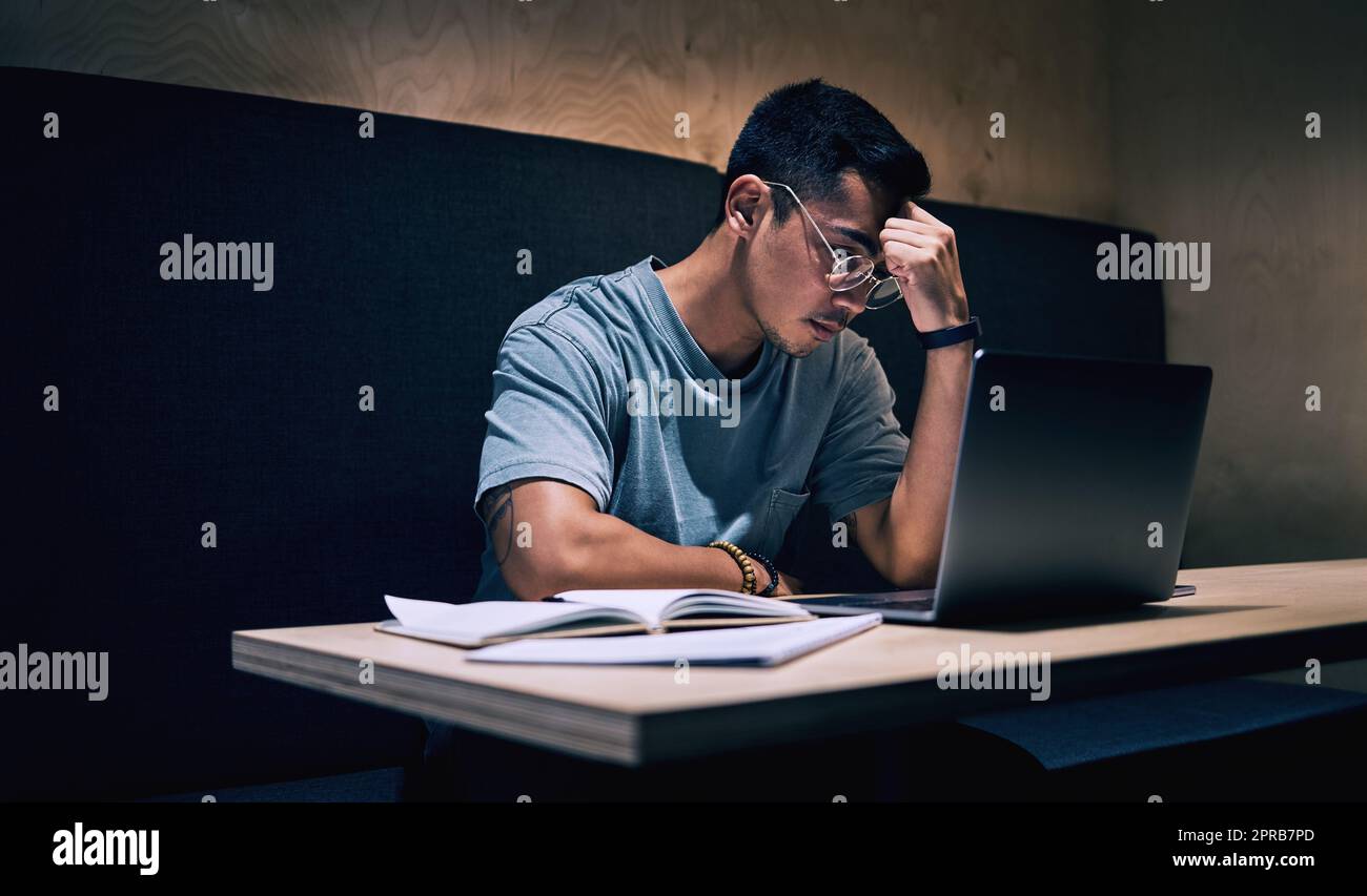 Questo lavoro è così stressante: Un giovane uomo d'affari appare stressato mentre usa il suo laptop per lavorare. Foto Stock