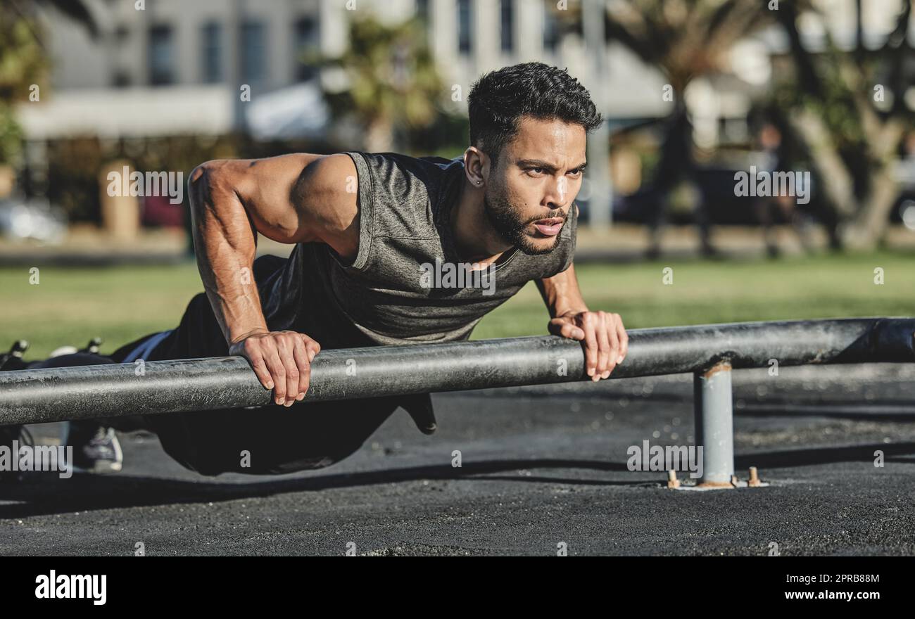 Il fitness non si ferma mai. Un giovane muscolare che si esercita in un parco calistenico. Foto Stock