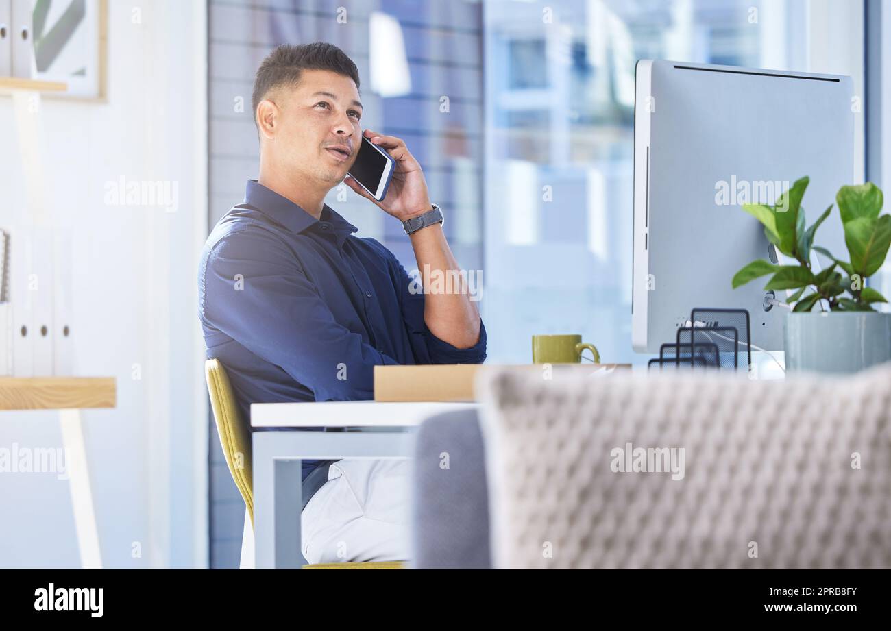 Quando volete incontrarvi, un uomo d'affari che parla sul suo cellulare mentre si siede alla sua scrivania. Foto Stock