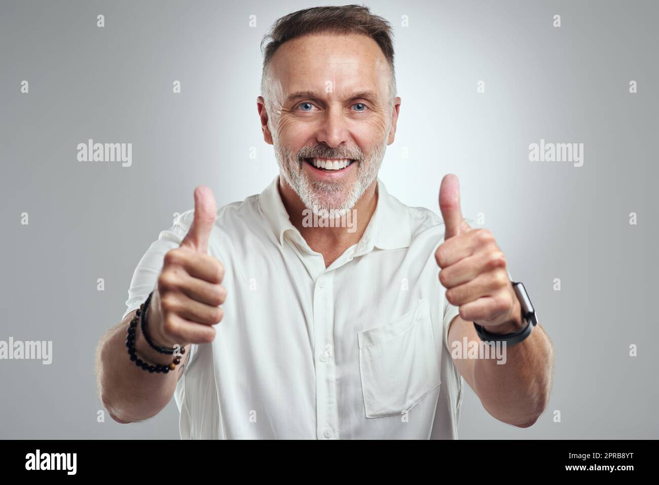 Sono così dannatamente orgoglioso di voi. Ritratto di studio di un uomo maturo che mostra i pollici su uno sfondo grigio. Foto Stock
