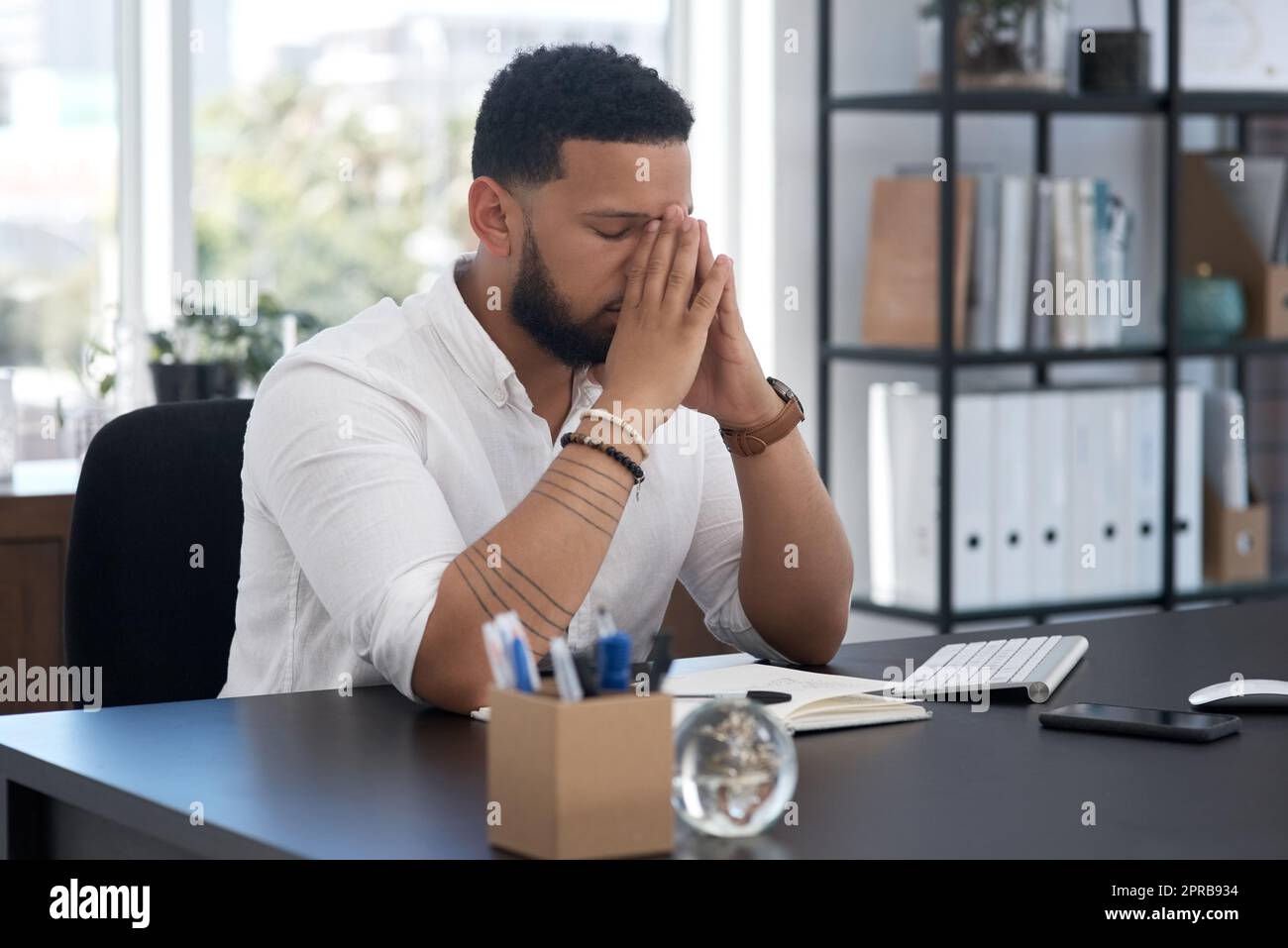 Come affronterò questo problema: Un giovane uomo d'affari che guarda stressato mentre lavora in un ufficio. Foto Stock