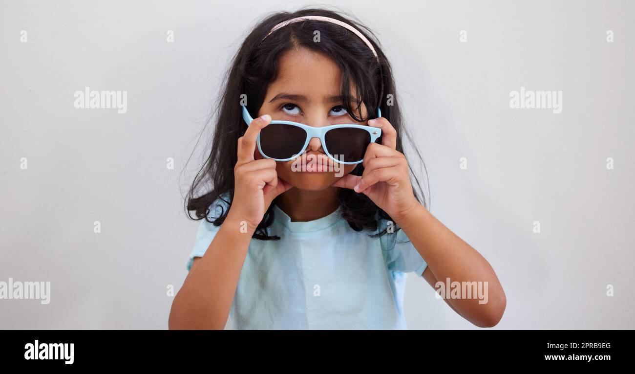 Nel caso in cui non riuscivate a vedermi rotolare gli occhi sotto gli occhiali, una bambina adorabile che guarda in su mentre rimuove i suoi occhiali da sole. Foto Stock