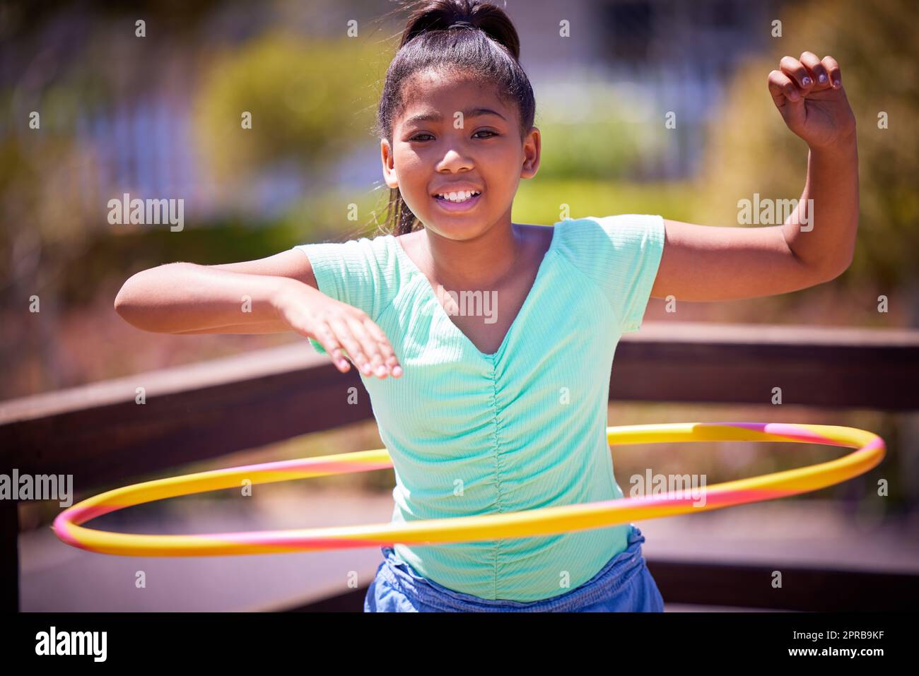 Mantenersi in forma e divertirsi. Ritratto di una ragazza carina che gioca con un cerchio di plastica al parco. Foto Stock