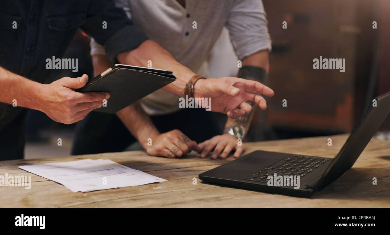 Utilizzo di strumenti moderni per un risultato migliore. Due uomini discutono di qualcosa su un notebook mentre si trovano in un'officina. Foto Stock