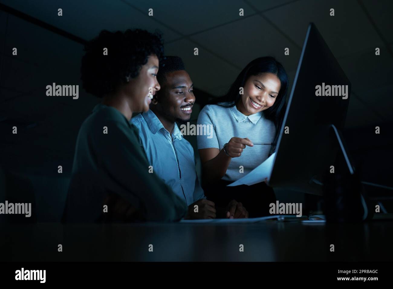 Un team solido lavora ai loro punti di forza. Un gruppo di giovani uomini d'affari che usano un computer insieme durante una notte tarda al lavoro. Foto Stock