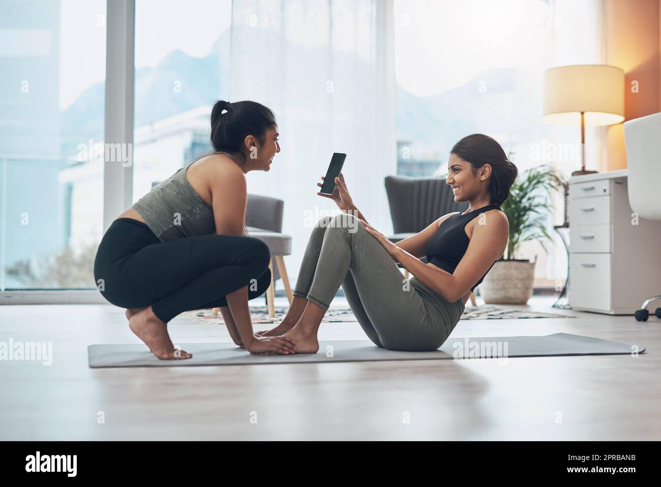 Lei mi motiva a continuare a fare, due belle giovani donne che si esercitano insieme a casa. Foto Stock