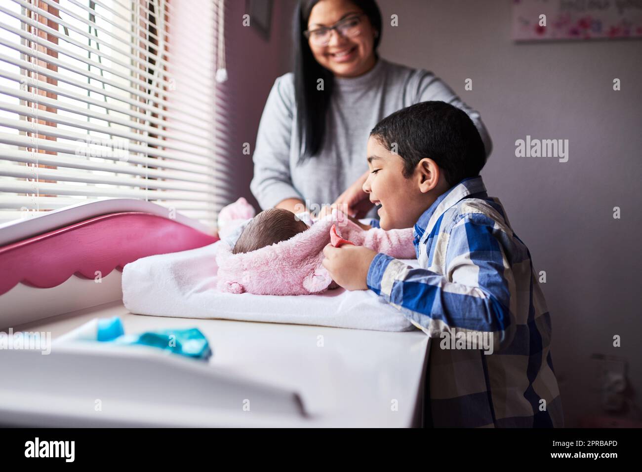 Un regalo dall'alto, una sorella nuova da amare, un adorabile ragazzino che si lega con la sorella appena nata nella camera da letto di casa. Foto Stock